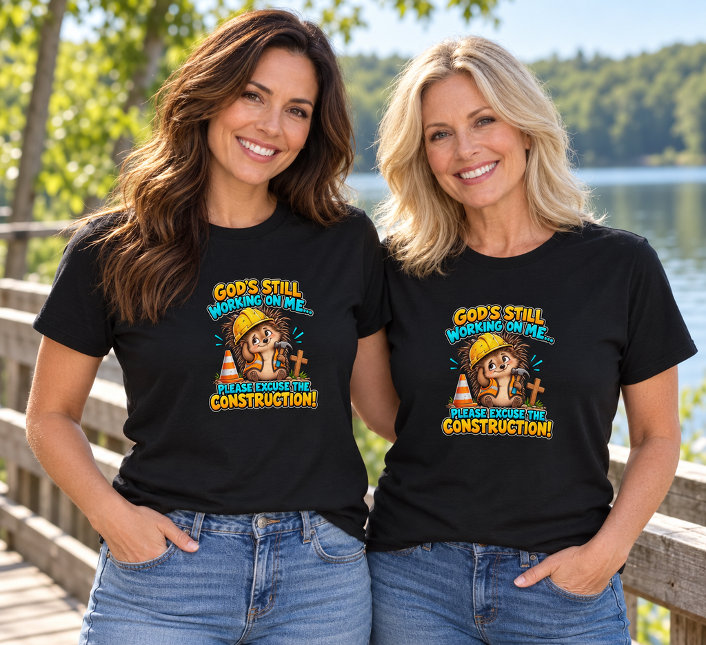 Two women wearing the God’s Still Working on Me Hedgehog Unisex T-Shirt in a pretty outdoor setting